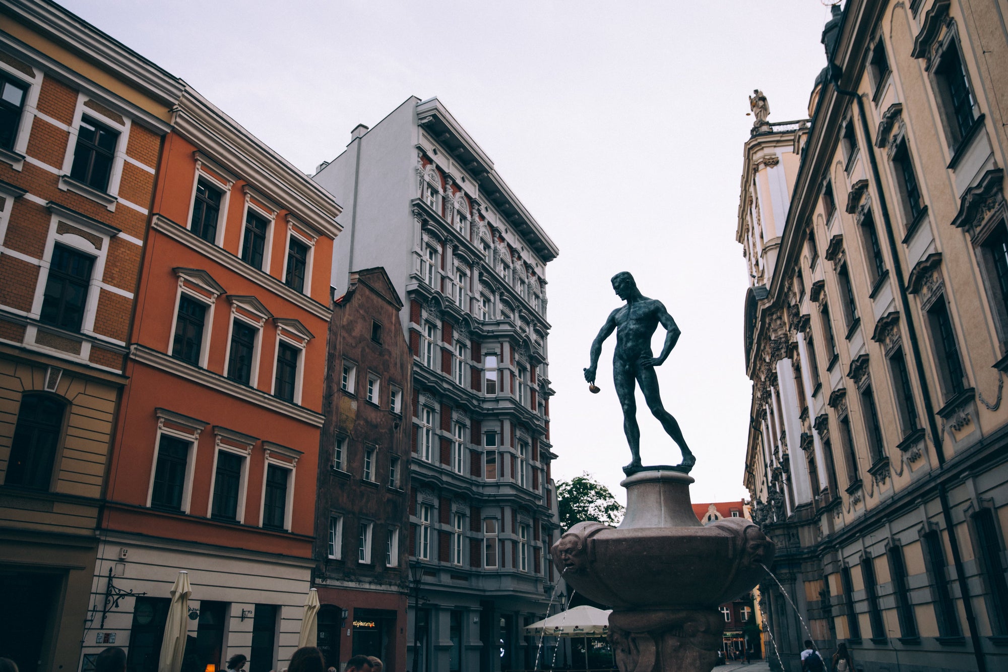 A statue of a man holding a ladle downtown in a city in Poland